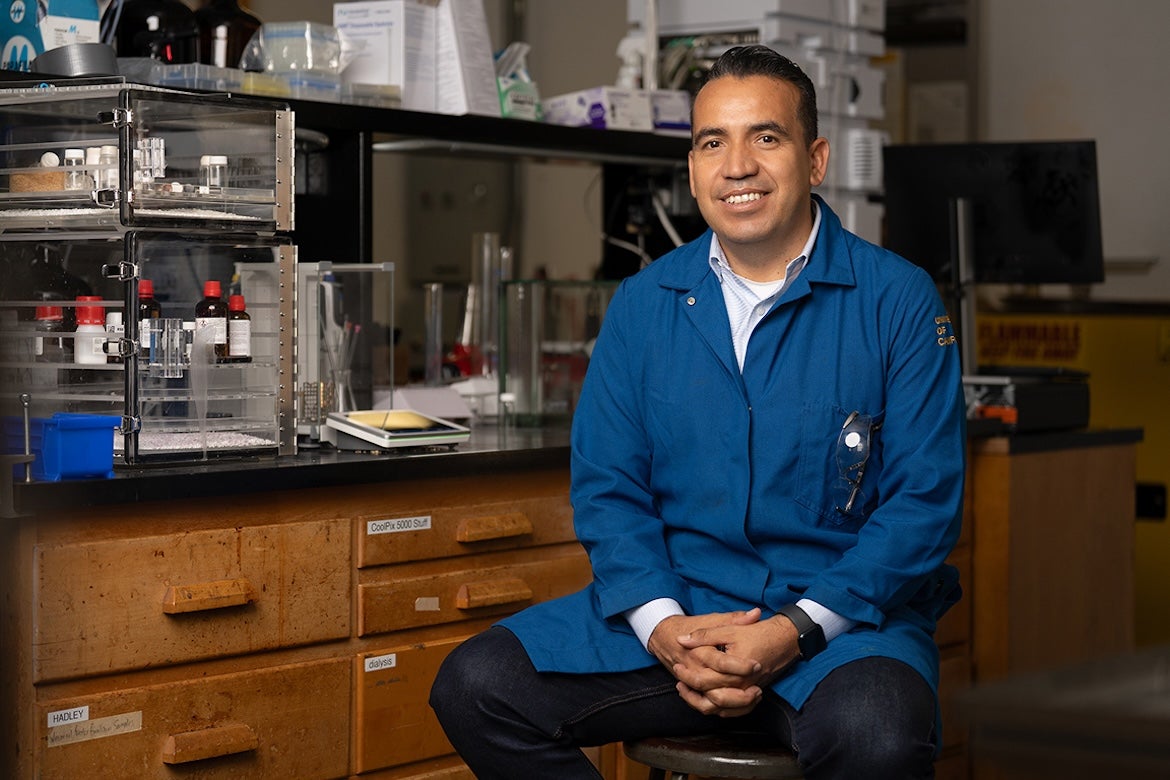 Osvaldo Gutierrez seated in lab wearing blue lab coat