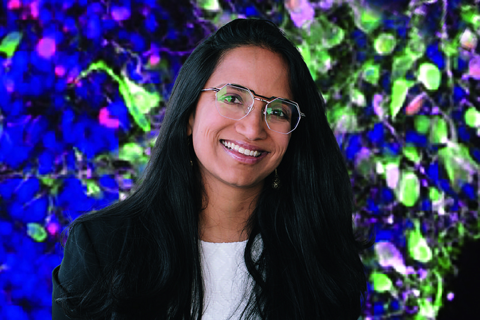 Assistant professor Aparna Bhaduri smiles in front of ivy plants